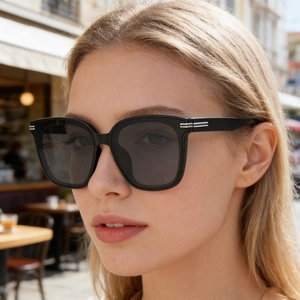 Détail de lunettes de soleil carrées noires avec barres métalliques argentées sur branches