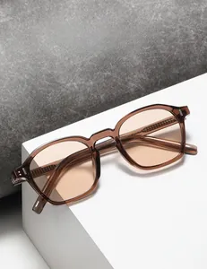 Detail of square amber sunglasses with metal hinges on a geometric stand