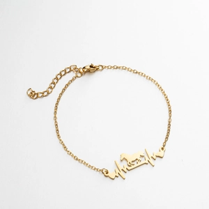 Makroaufnahme der goldenen Armband-Kette mit Herzschlag und laufendem Pferd-Anhänger