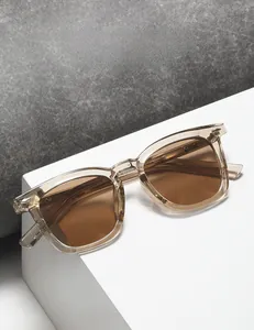 Détail de lunettes de soleil carrées avec monture champagne et rivets métalliques argentés