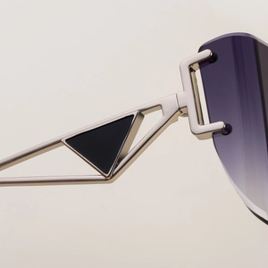 Macro detail of silver metal temple with iconic black triangle logo on rimless sunglasses