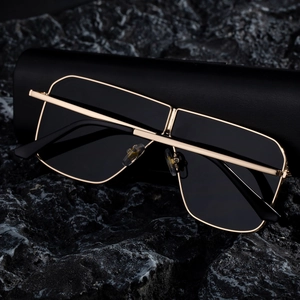 Detail of square gold metal sunglasses resting on a premium black hardshell eyewear case