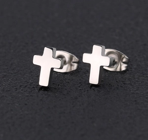 Macro shot of silver stainless steel cross stud earrings on black textured leather