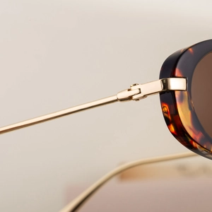 Detail of tortoise shell frame and gold metal hinge of vintage oval sunglasses