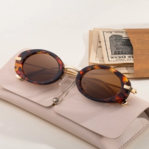 Oval tortoiseshell sunglasses with brown lenses and a leather case in a vintage setting