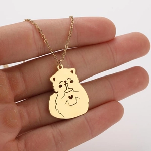 Close-up of golden cartoon cat pendant necklace with heart detail held in hand