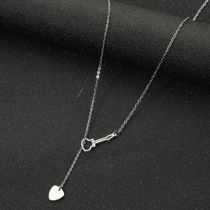 Détail d'un collier guitare en acier avec pendentif cœur sur fond noir texturé élégant