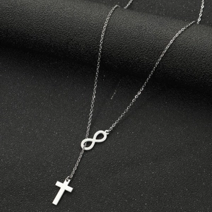 Detail of silver infinity and small cross pendant on a thin stainless steel necklace