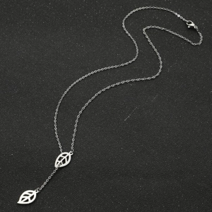 Silver Y-necklace with elegant double hollow leaf pendants on a textured black surface