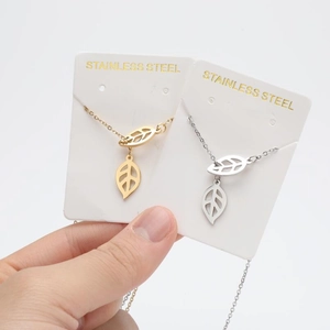 Detail of hollow leaf pendant on gold and silver stainless steel necklace chain