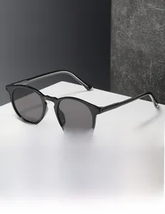 Close-up of modern round frame sunglasses with polished black frames on a white platform