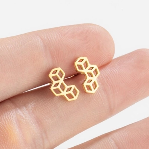 Minimalist gold geometric hollow cube stud earrings shown in a hand-held close-up view