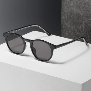 Classic round frame sunglasses for women in black with dark grey lenses on white platform