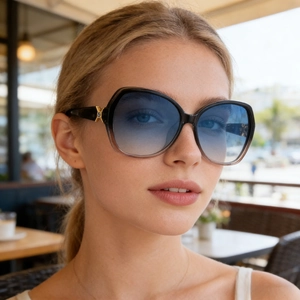 Nahaufnahme der Damen-Schmetterlingsbrille mit blauen Verlaufsgläsern und goldenem X-Detail
