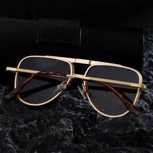 Détail de lunettes pilote carrées avec monture en métal doré et embouts en écaille