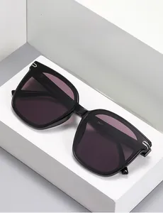 Detail of polarized lenses and silver U-shaped metal hinge on black square sunglasses