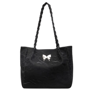 Detail of black tote bag with silver butterfly metal piece and woven handle design