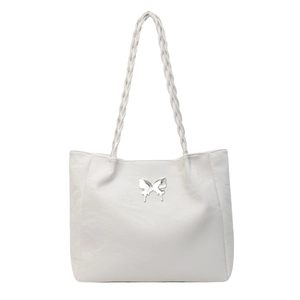 Close-up of white tote bag with silver butterfly logo and braided shoulder strap