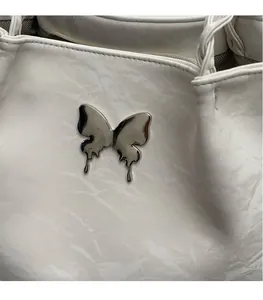 Detail shot of a cream leather tote bag featuring a silver butterfly buckle and woven strap