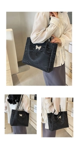 Detail of black pleated tote bag with silver metal butterfly and woven rope straps
