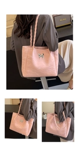 Detail of pink pleated tote bag featuring a butterfly metal clasp and woven strap