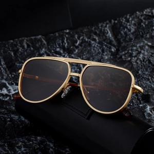 Lunettes de soleil aviateur dorées rétro avec verres bruns sur roche et étui cuir