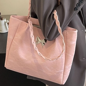 Pink pleated tote bag with silver butterfly charm and woven shoulder strap on model