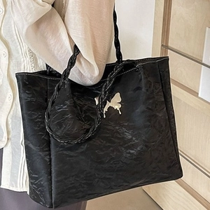 Retro black tote bag with white butterfly print and woven rope handle shown on shoulder