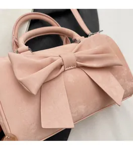 Detail of soft pink suede handbag with large bow decoration and silver metal hardware