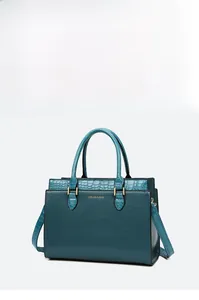 Detail view of teal tote bag with crocodile embossing and golden hardware accents