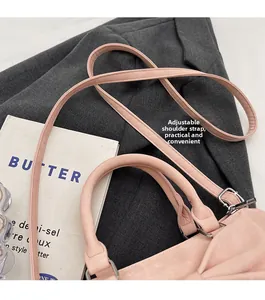 Detail of pink bow bag showing adjustable strap and silver hardware on a suit background