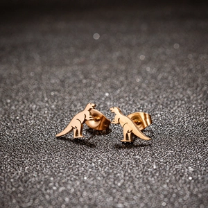 Cute dinosaur stud earrings in rose gold finish on a sparkling black background