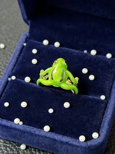 Macro shot of green enamel frog ring with gold accents in a blue velvet box