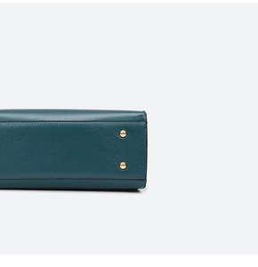 Macro view of dark green pebbled leather bag bottom with protective gold metal studs