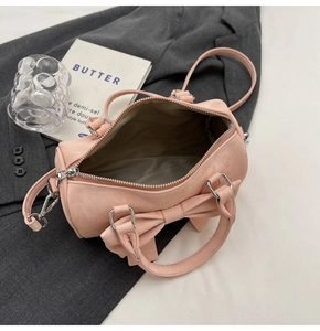 Pink bow-knot barrel handbag featuring smooth faux leather texture and top zipper detail