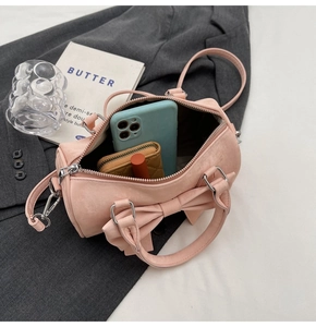 Pink bow-knot mini cylinder bag showing interior space for phone and wallet essentials