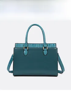 Detail of teal leather tote bag featuring crocodile pattern texture and golden logo text