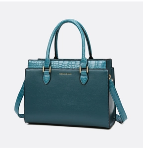 Detail of dark green tote bag featuring lychee and crocodile texture with gold lettering