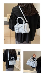 Detailed close-up of light blue cylinder bag with large bow decoration and matte finish