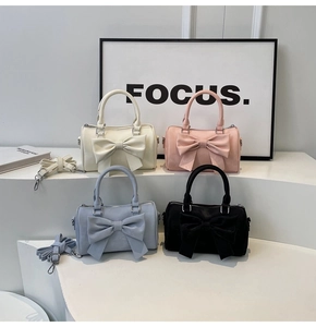 Front view of four stylish bow-knot boston bags in cream, pink, blue, and black colors