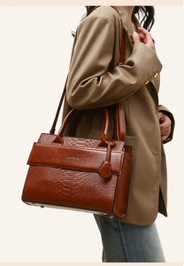Detail view of the crocodile pattern texture and metal bottom rivets on dark brown tote bag