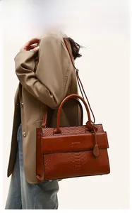Detailed side view of a brown crocodile pattern tote bag with metal logo and shoulder strap
