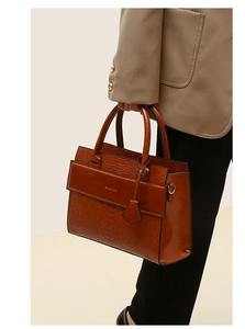 Detail of vintage brown tote bag featuring crocodile embossed leather and sturdy handles