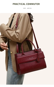 Detail of burgundy crocodile-embossed tote bag featuring dual handles and shoulder strap