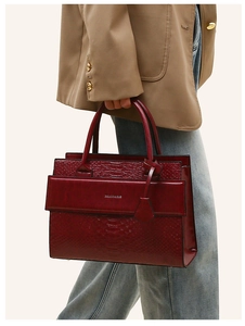 Close-up of crocodile texture and golden hardware on a burgundy leather handbag