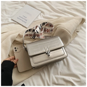 Silver square crossbody bag with wide jacquard strap and phone for size reference