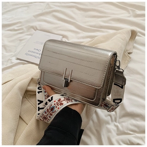 Detail of silver metallic crossbody bag featuring floral embroidered and logo wide straps