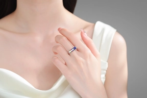 Close-up of elegant rainbow zircon silver ring on finger with luxury silk background