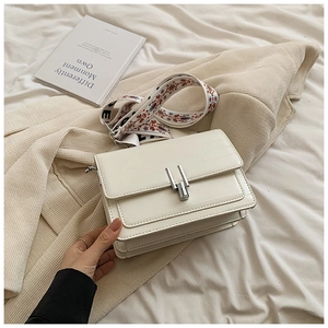 Close-up of white crossbody bag with silver buckle and bohemian jacquard strap