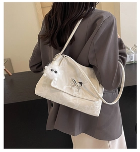 Detail of white embossed tote bag with silver butterfly buckle and furry charm accessory
